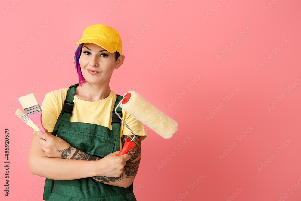 戴帽子的女油漆工，粉色背景上有油漆滚筒和刷子
