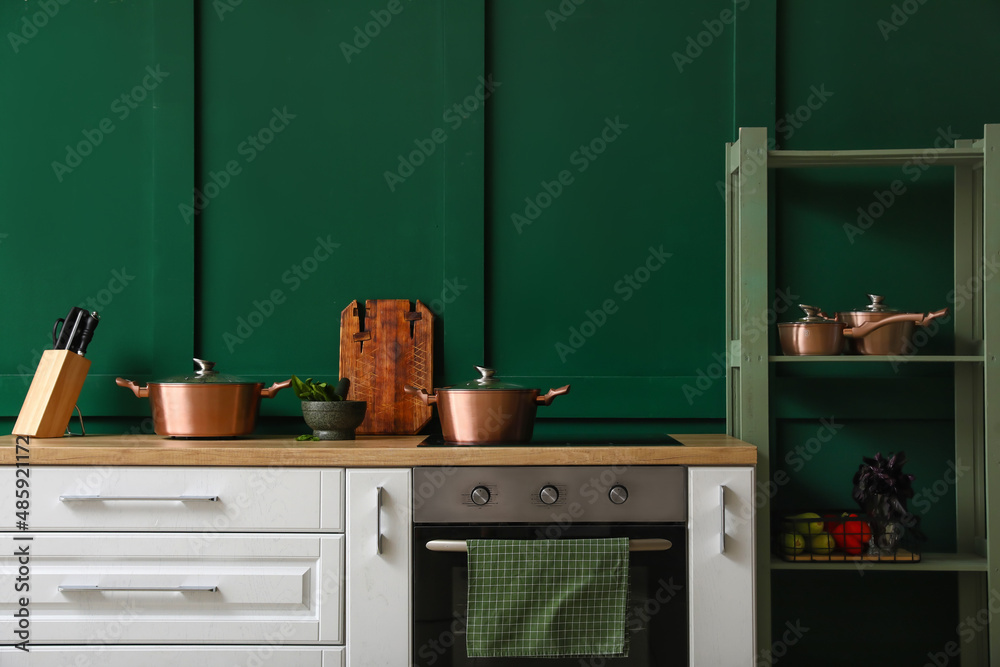 靠近彩色墙的木制餐桌和搁架单元，带厨房用具