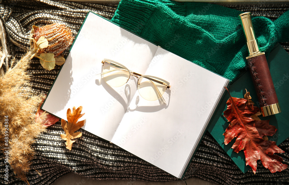 格子布上的空白书、眼镜和秋季装饰