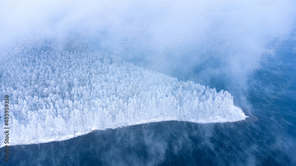 从上方俯瞰冬季积雪覆盖的森林岛和结冰的湖泊全景