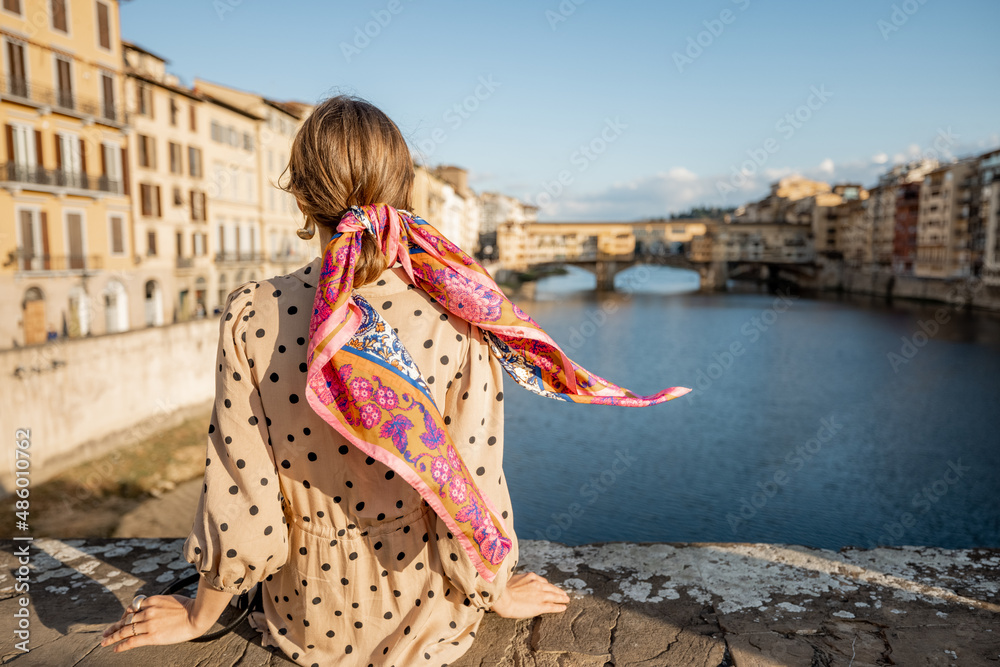年轻女子坐在佛罗伦萨著名的老桥上欣赏美景。
