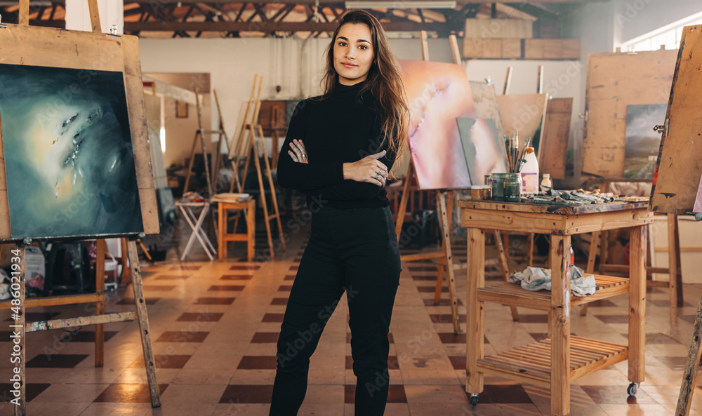 Professional painter standing in her atelier with her arms crossed