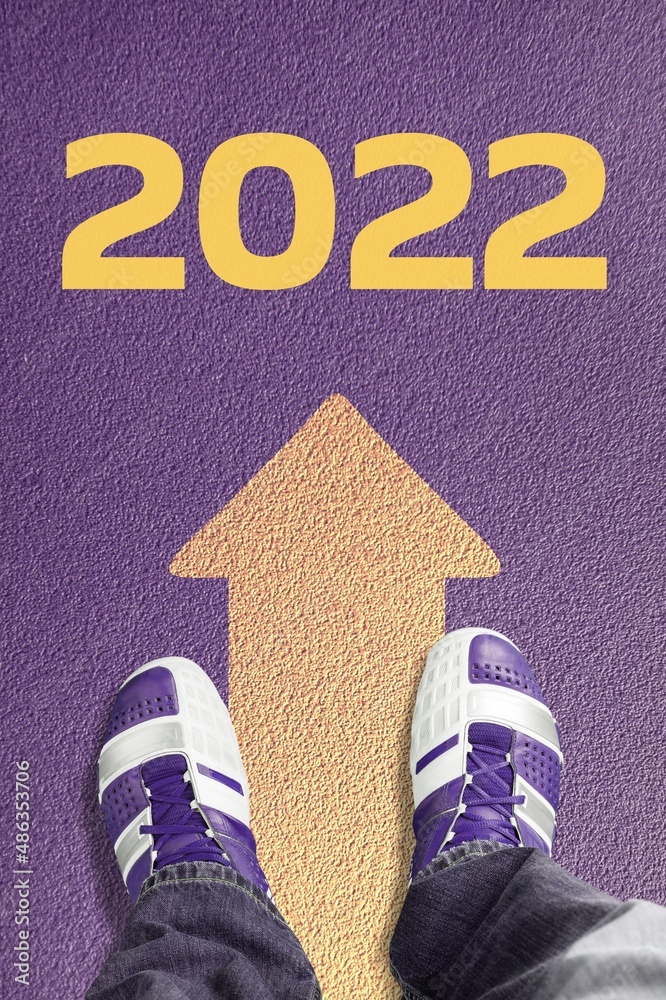 2022年新年或直接开始概念。写在柏油路上和脚上的2022字