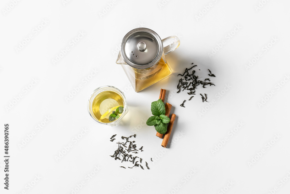 Composition of teapot and glass with tasty tea on light background