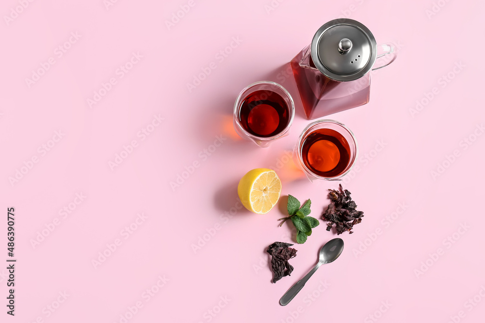 粉红色背景的茶壶、几杯美味的茶和香料