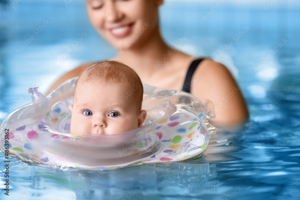 Adorable baby with inflatable ring and mother in swimming pool, closeup