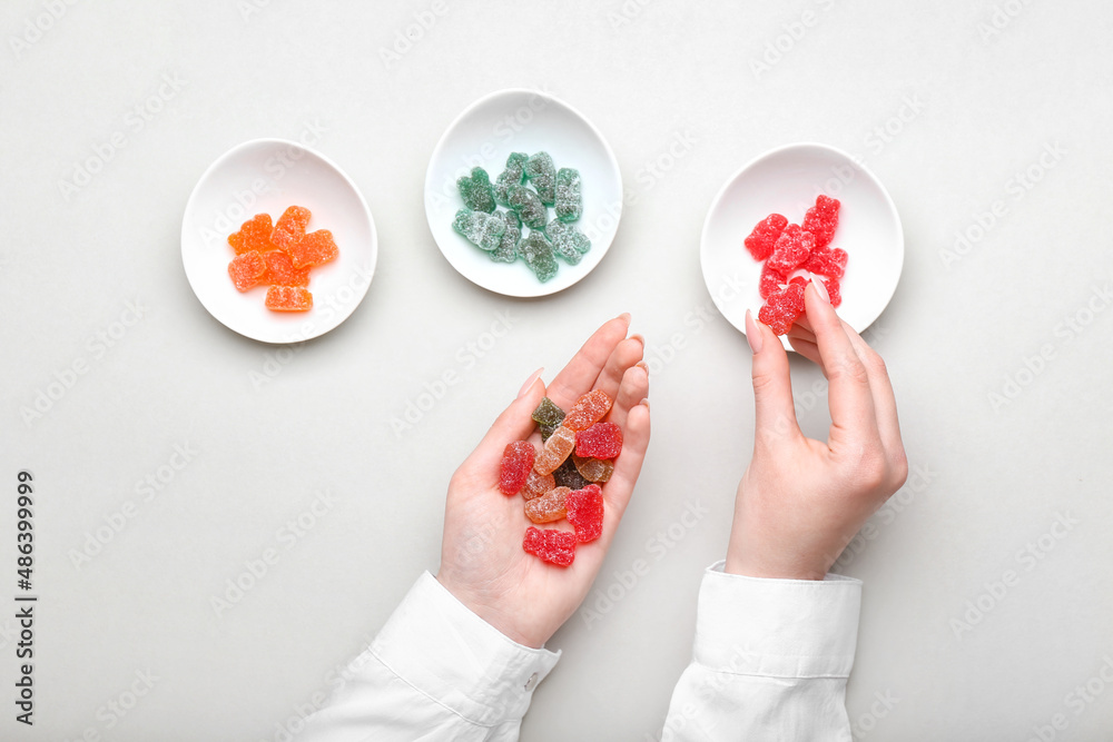 Woman holding jelly bears on light background