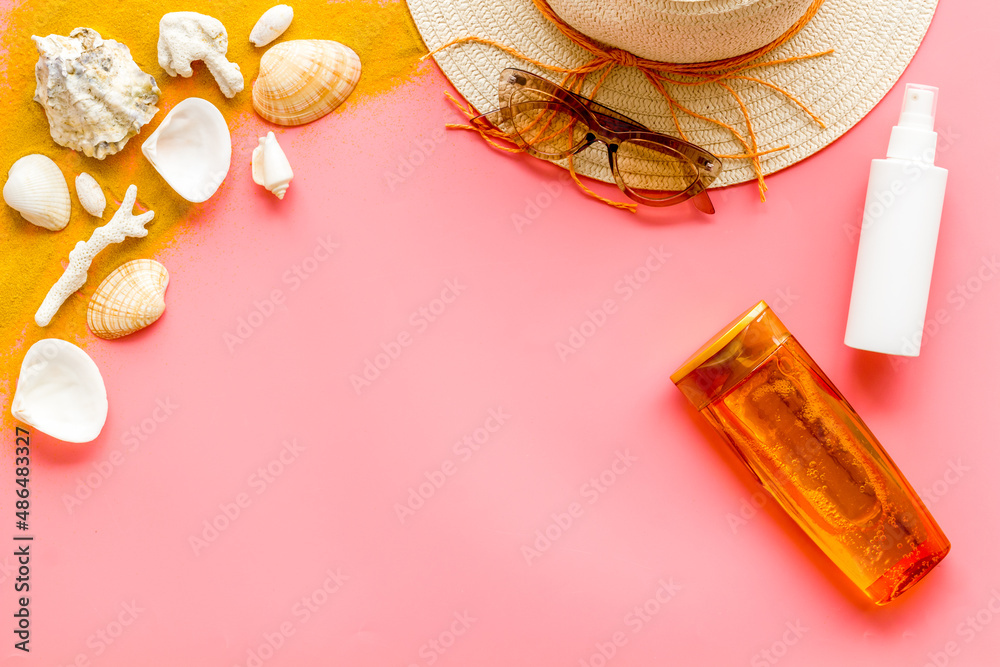Beach sand and seashells with straw hat and bottles od sunscreen