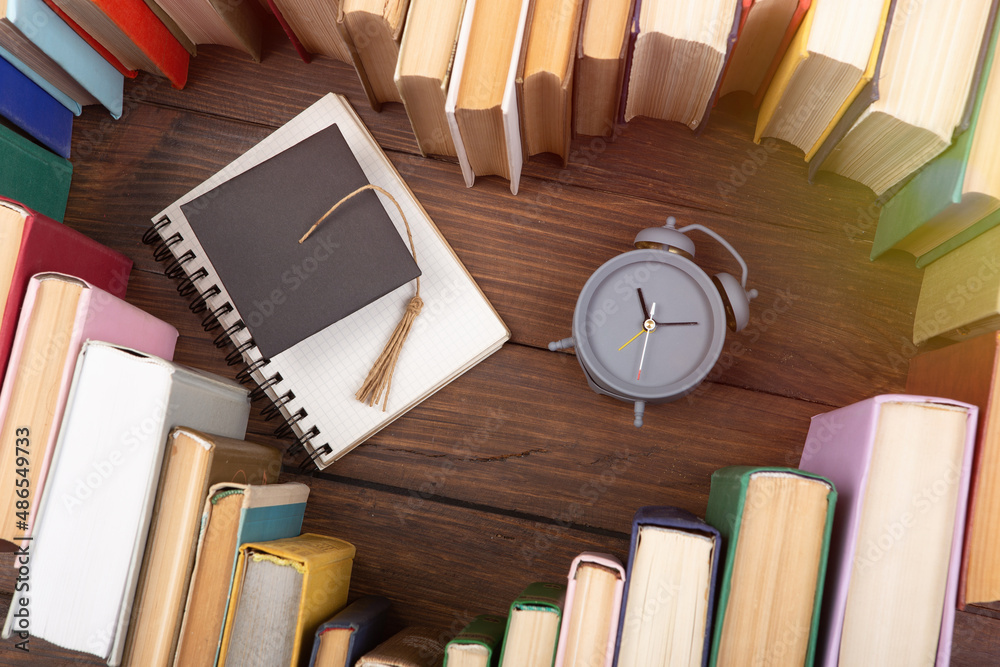 热爱科学概念。书籍的心形，木制桌子上的毕业帽和时钟。是时候休息了
