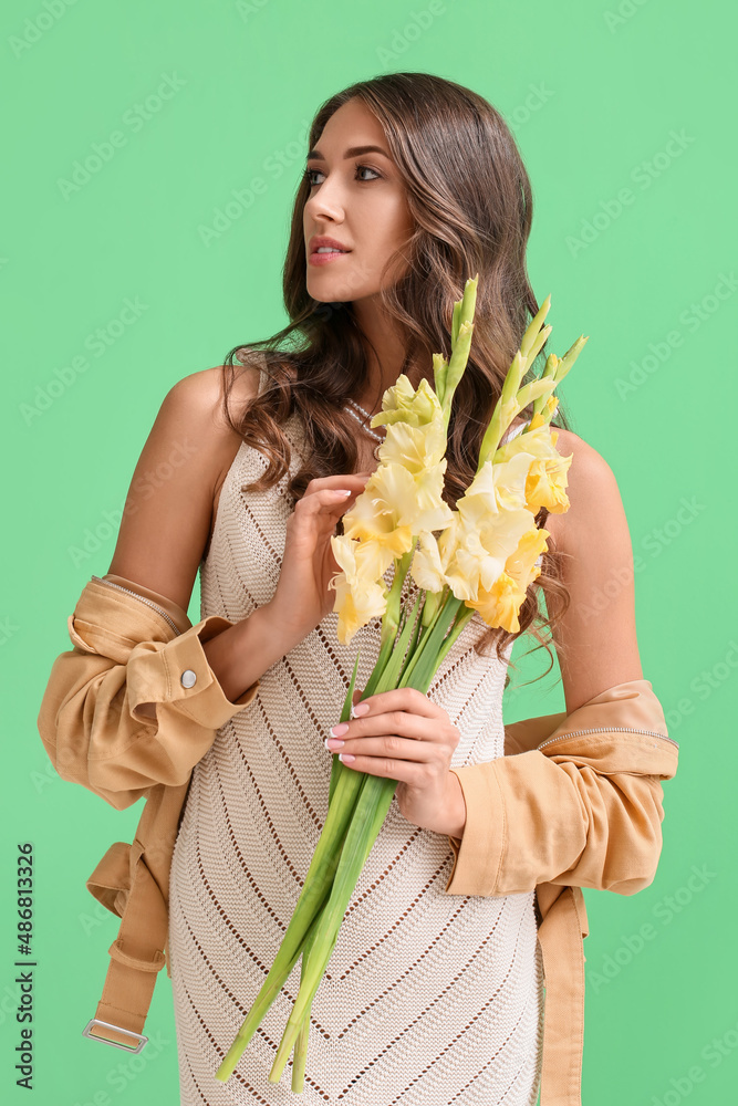 年轻优雅的女人，带着唐菖蒲花的花束，在绿色背景下眺望远方