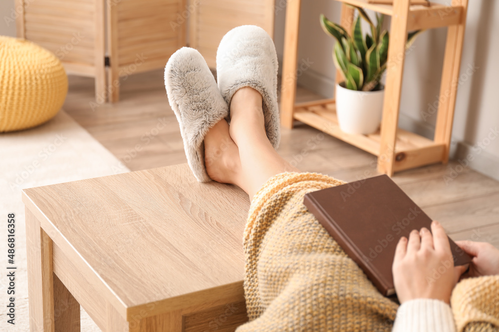 穿着柔软舒适拖鞋的年轻女子在家看书