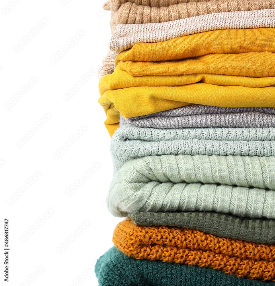 Stack of stylish folded sweaters on white background, closeup