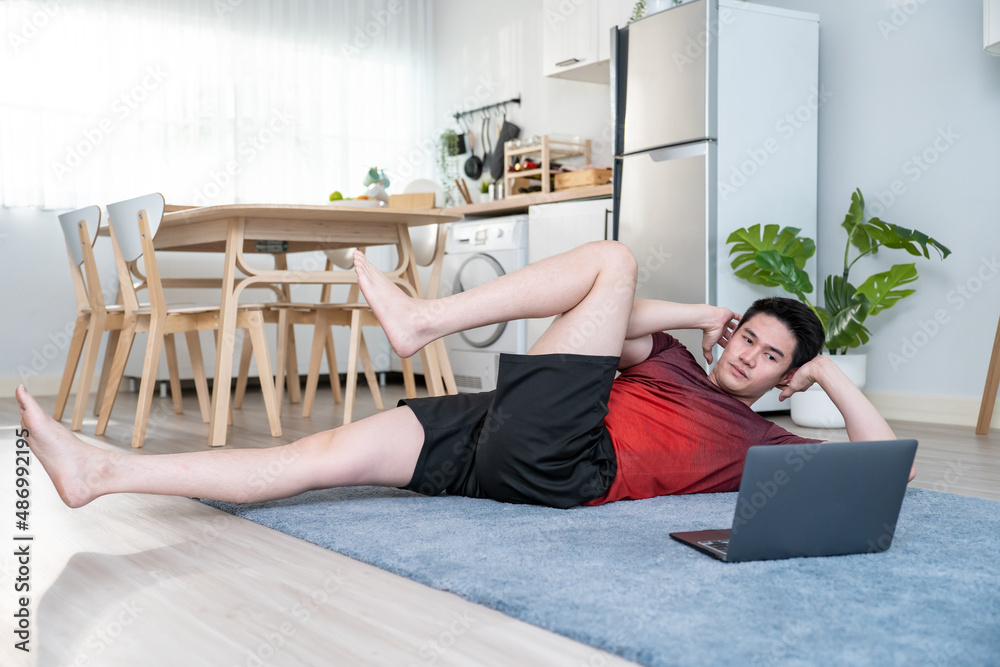 Asian handsome active young man doing exercise on floor in living room. 