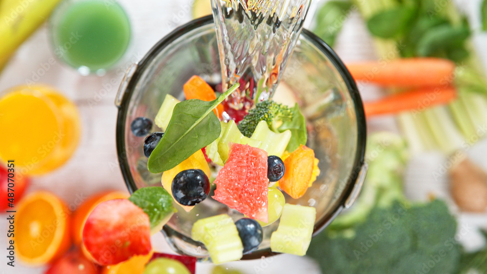 Falling pieces of fruits and vegetables into blender.
