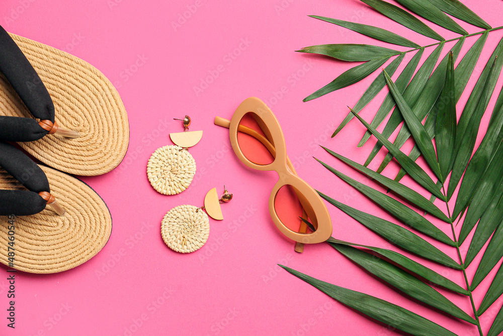 时尚的太阳镜、耳环、人字拖和彩色背景的棕榈叶