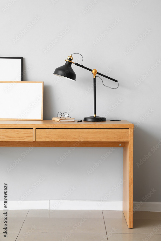 黑色灯，带笔记本、眼镜和镜框，放在靠近光墙的桌子上