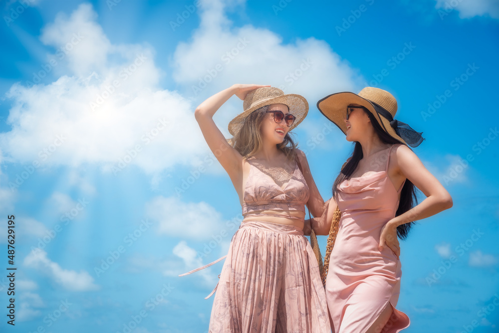 两个穿着稻草裙的快乐旅行者女人的肖像在夏季热带海滩上尽情享受
