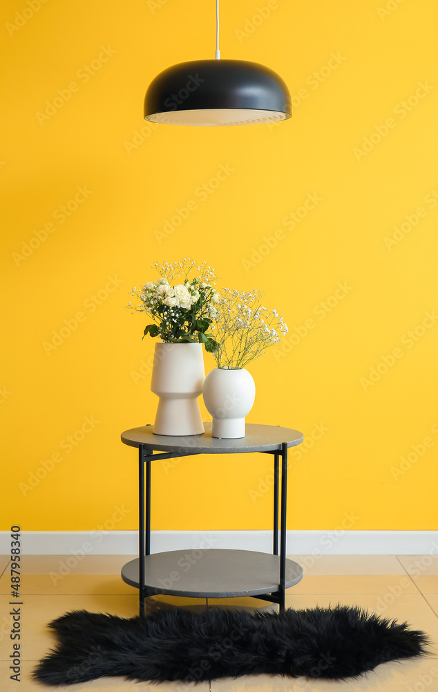 黄色墙壁附近桌子上放着玫瑰和吉普赛花的花瓶