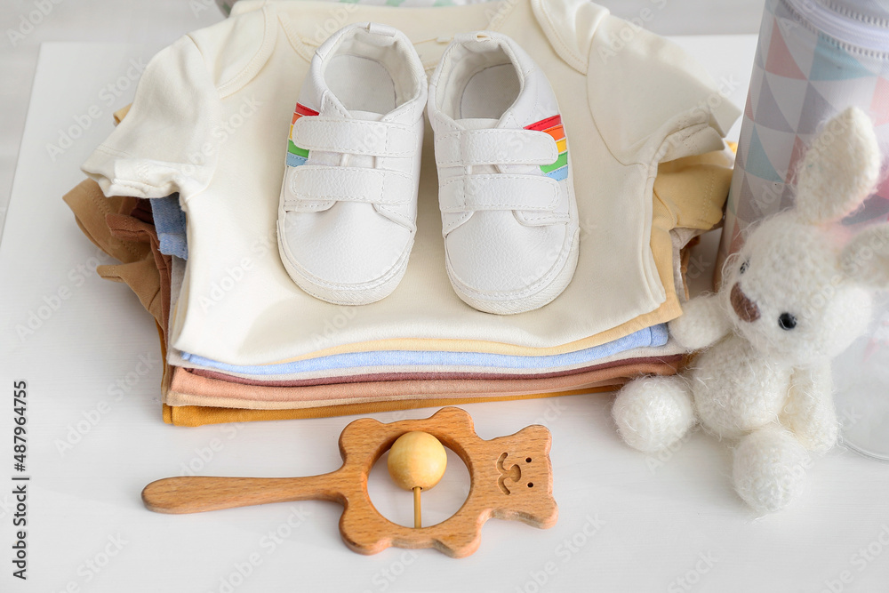 白色桌子上的一堆婴儿衣服、鞋子和玩具，特写