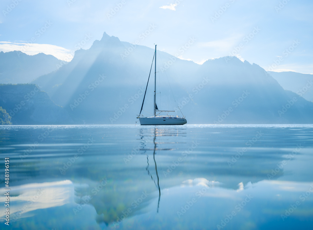 A yacht against the backdrop of the mountains in Switzerland. Calm water and bright sunny day. A pop