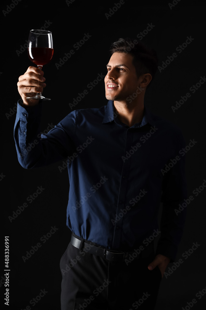 年轻男性侍酒师在深色背景下品尝葡萄酒