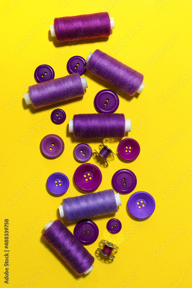 Different sewing threads with buttons on yellow background