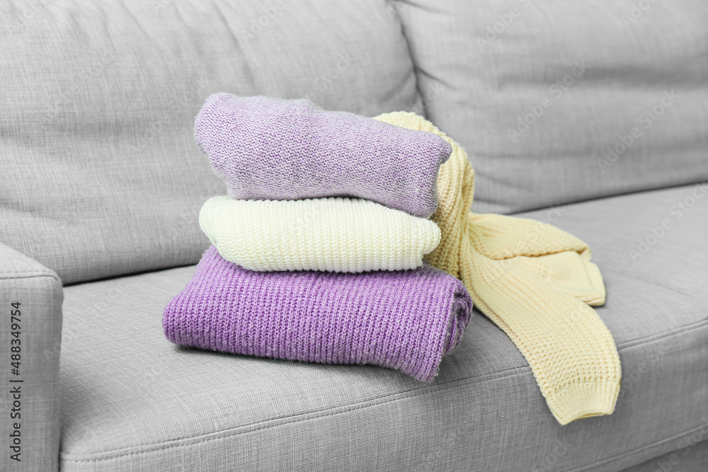 Stack of knitted sweaters on sofa