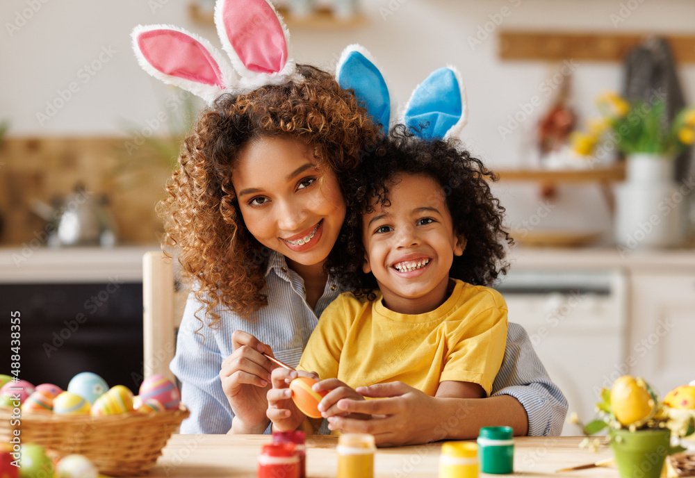 快乐的非裔美国人家庭：母亲教快乐的小孩很快装饰复活节彩蛋