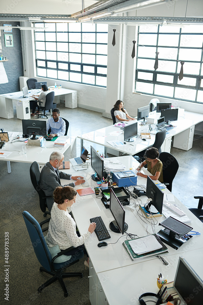 Everyones focused on their tasks. Shot of a group of coworkers sitting at their workstations in an o