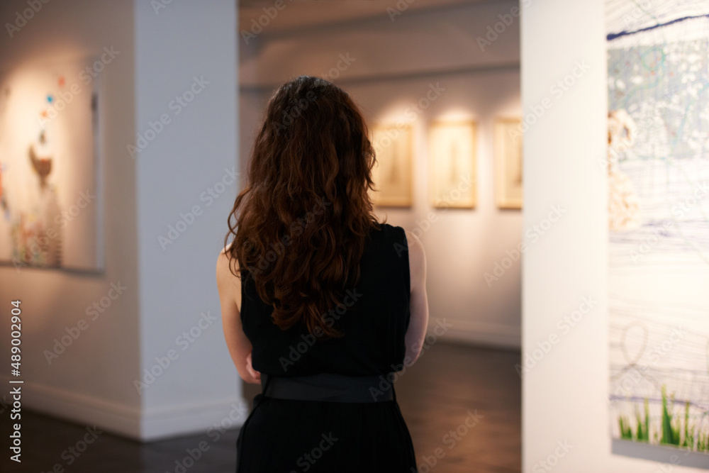 欣赏一个世纪的艺术。一个年轻女人在画廊里看画的镜头。