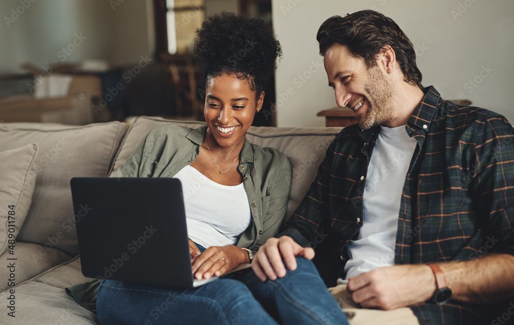 Were updating all our blogs today. Shot of a happy young couple using a laptop while relaxing on a c