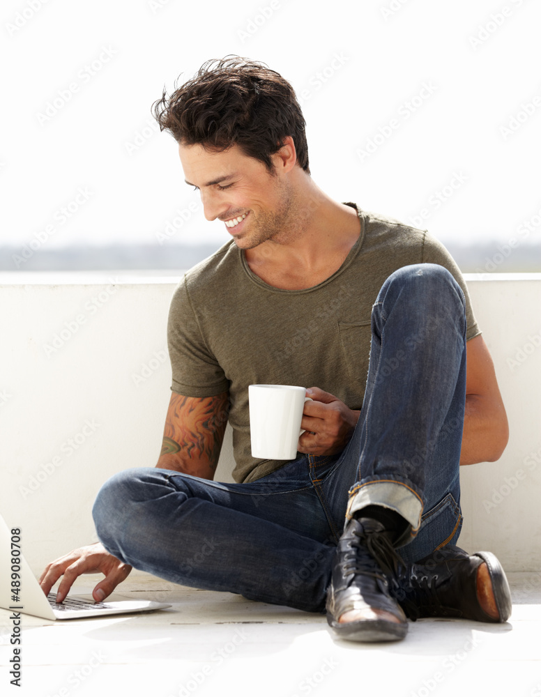 在外面上网。一个英俊的年轻人坐在外面用笔记本电脑喝咖啡