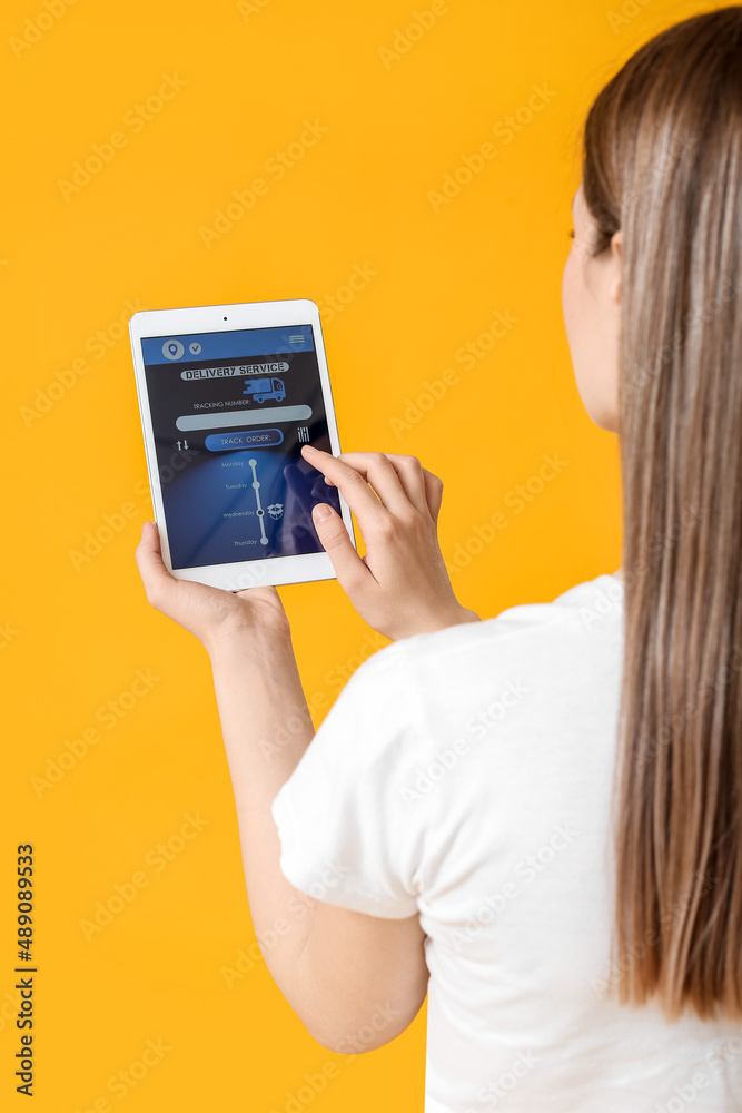 年轻女子用平板电脑在彩色背景下使用快递服务应用程序