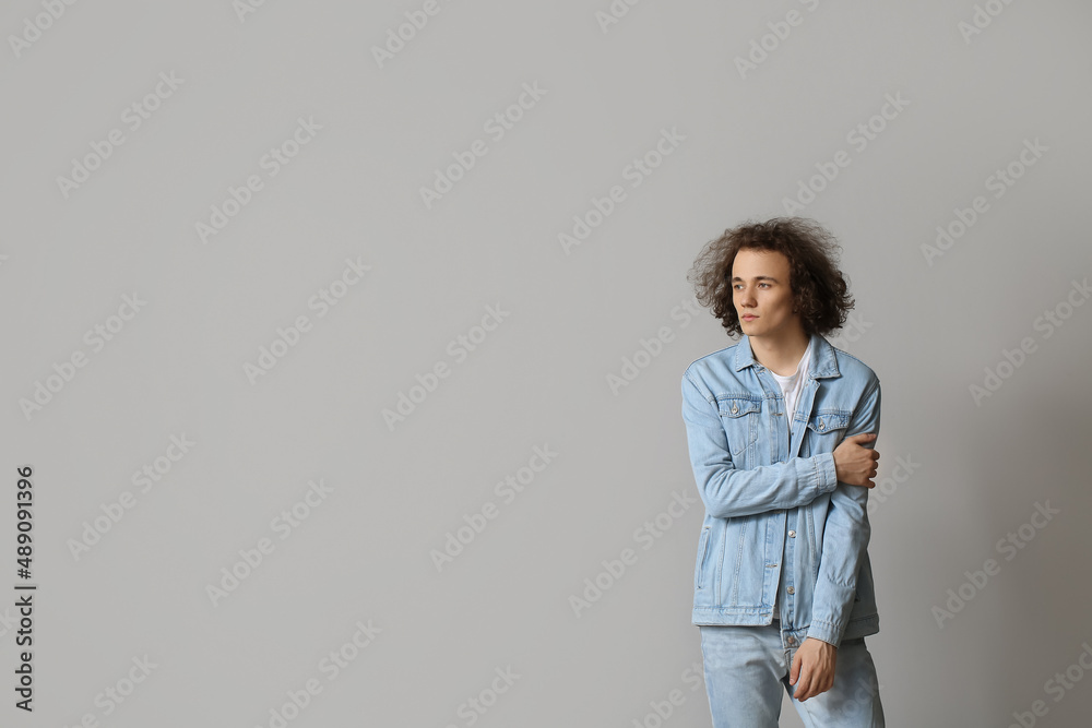 Fashionable young man in stylish jeans clothes on light background