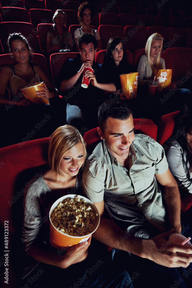 We found love at the movies. A happy young couple watching a movie at the cinema together.