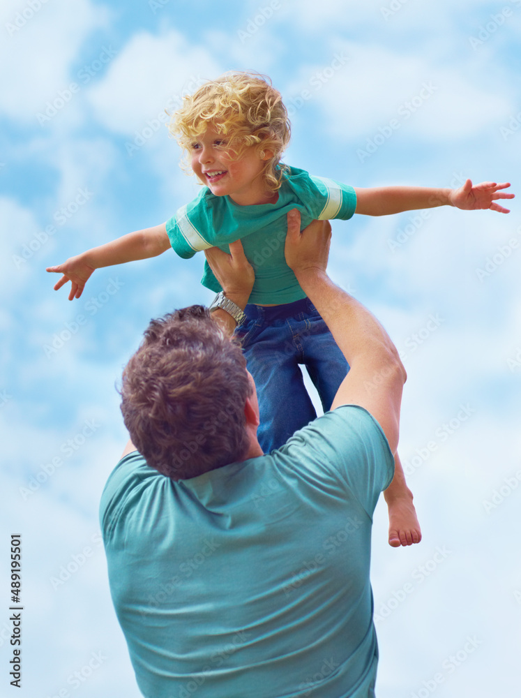 Daring to dream. A father swinging his toddler son in the air against a sky background.