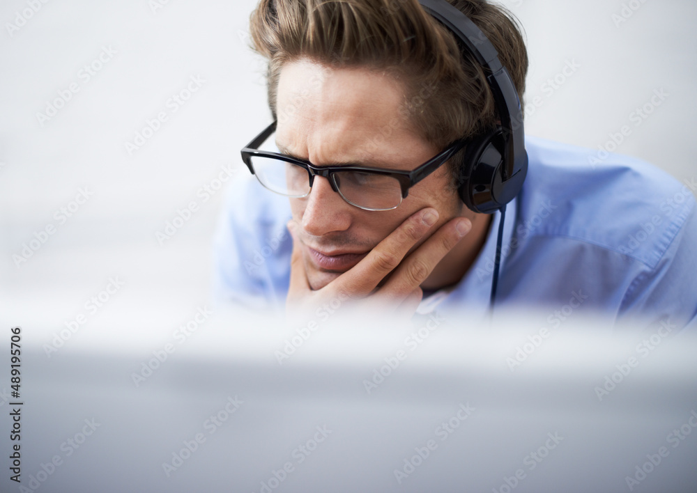 Absorbed in his work. A handsome young businessman wearing a headset while concentrating on his comp