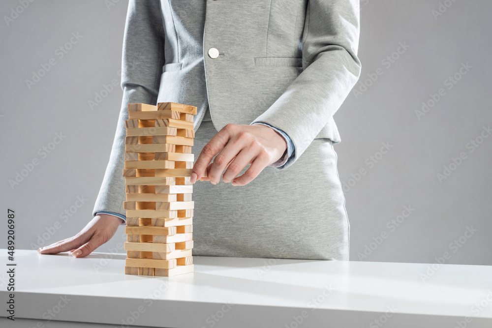 Businesswoman removing wooden block from tower