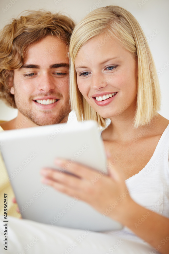 用户直观。一对年轻夫妇在舒适的沙发上用平板电脑浏览互联网