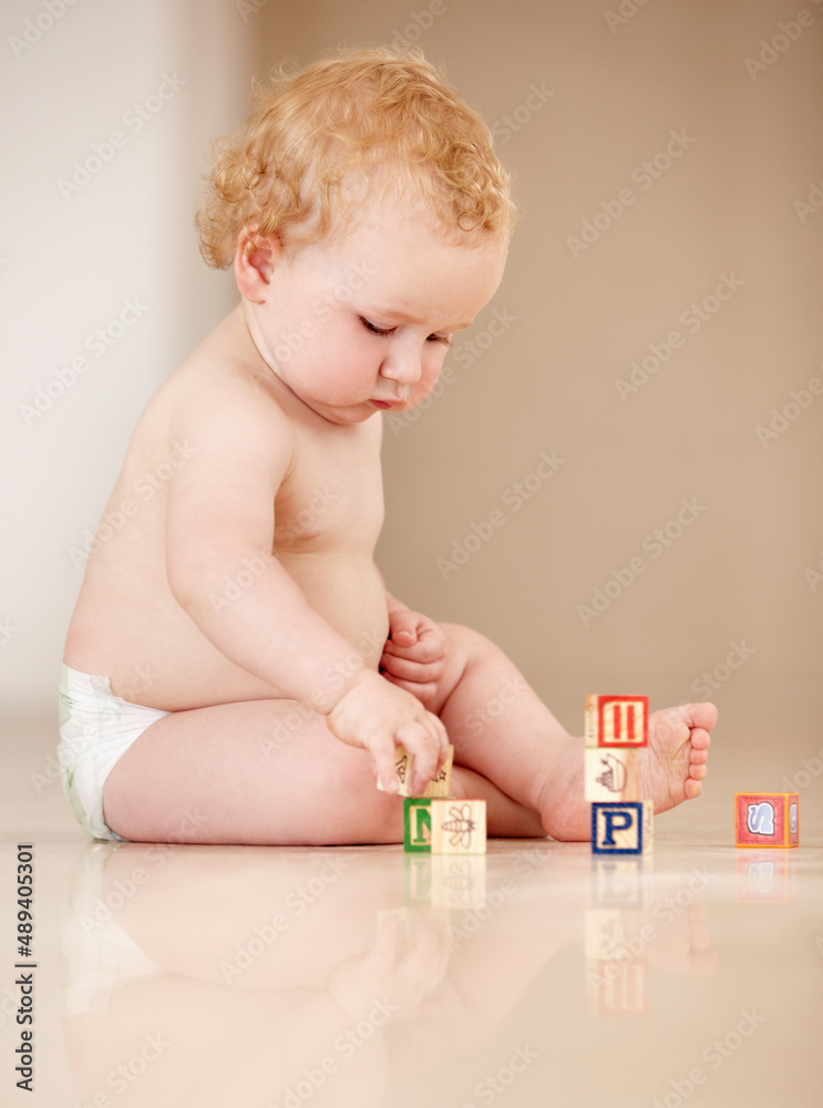 通过互动学习。可爱的小婴儿坐在地上玩字母表