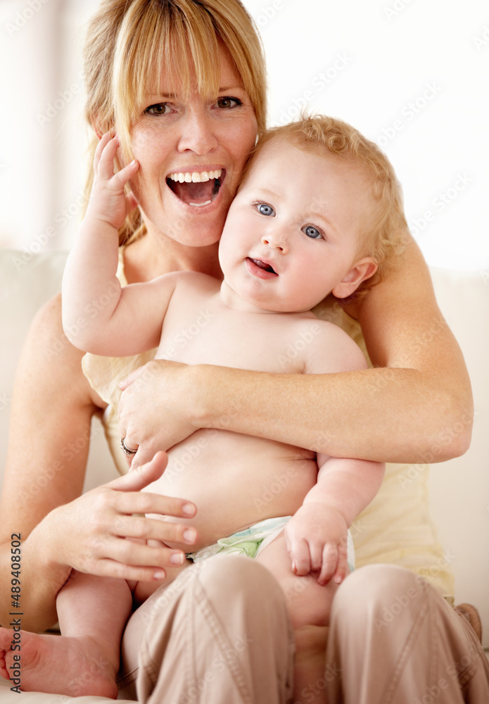 妈妈，小天使。大笑的妈妈把她的男婴抱在腿上。