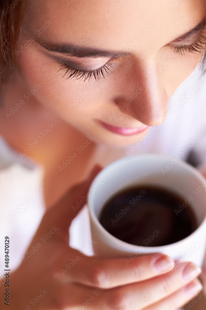 以一杯新鲜的咖啡开始新的一天。一个年轻女人一边喝着咖啡，一边看起来若有所思