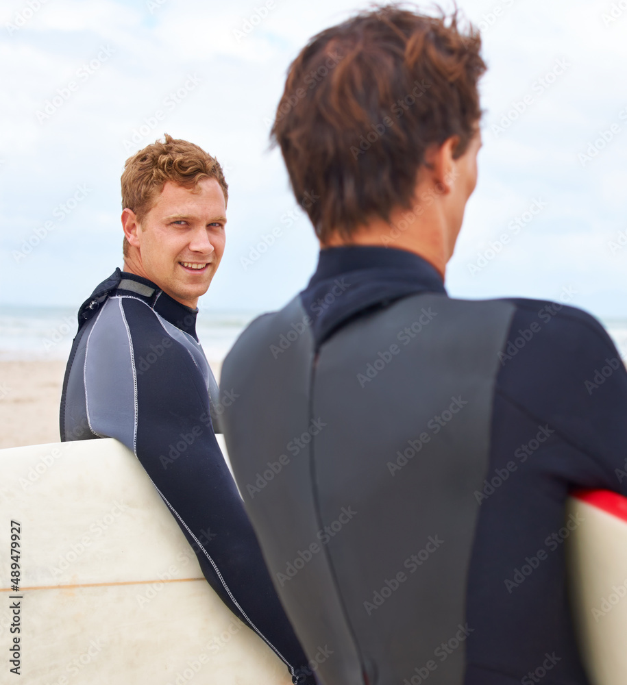 被他们对冲浪的热爱所束缚。两个年轻的冲浪者站在海滩上，背后是大海