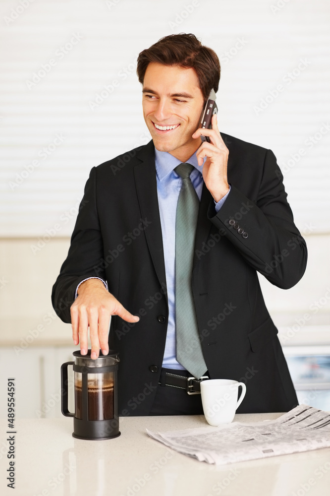 Happy executive using cellphone while drinking coffee at home. Happy young executive using cellphone