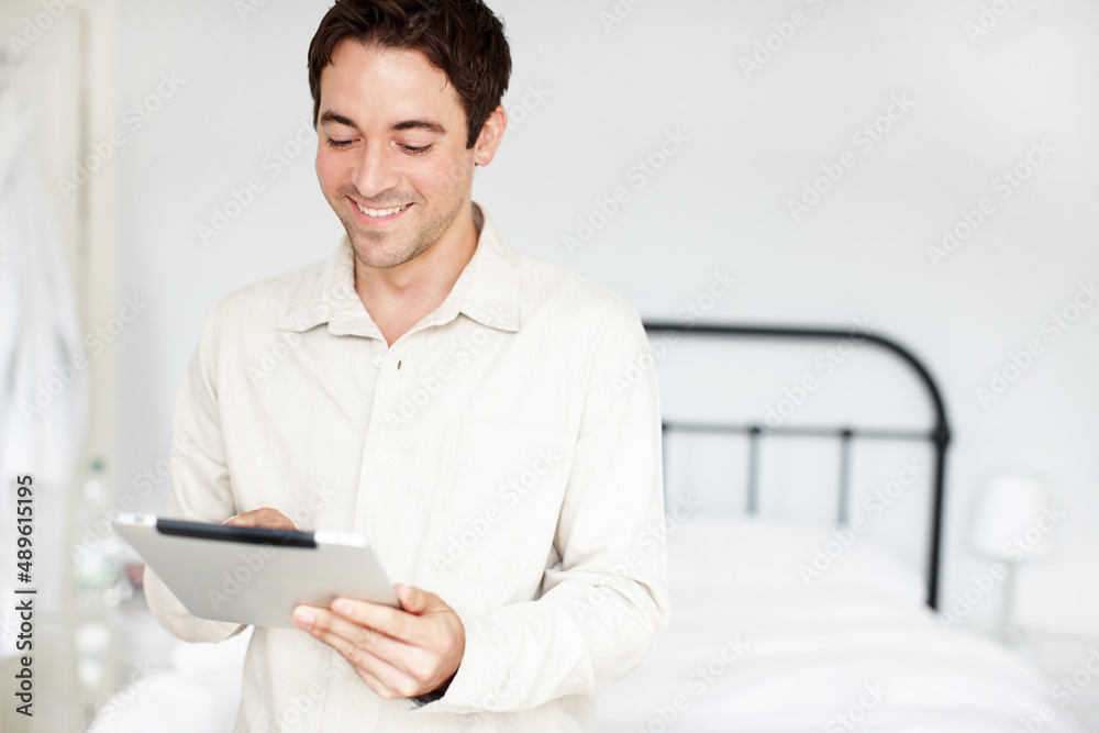 在舒适的房间里查看电子邮件。快乐的年轻人拿着他的数字平板电脑办理登机手续