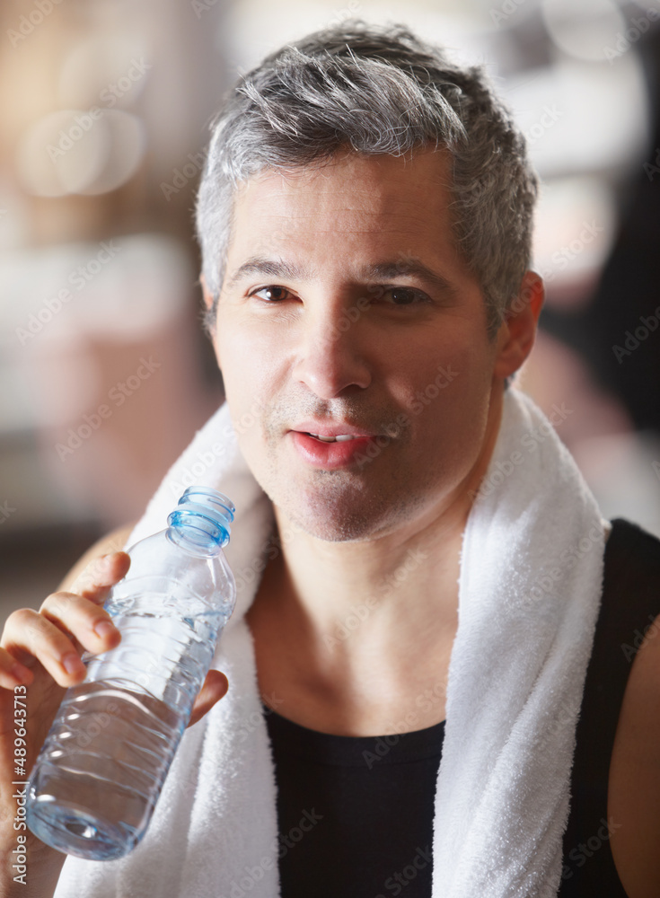 锻炼后急需水。一个成年男子在锻炼后用水瓶喝水的肖像