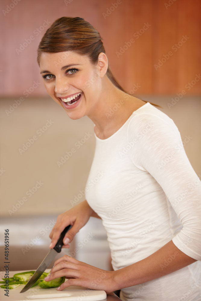 她喜欢烹饪。一个美丽的年轻女子在厨房里烹饪的画像。