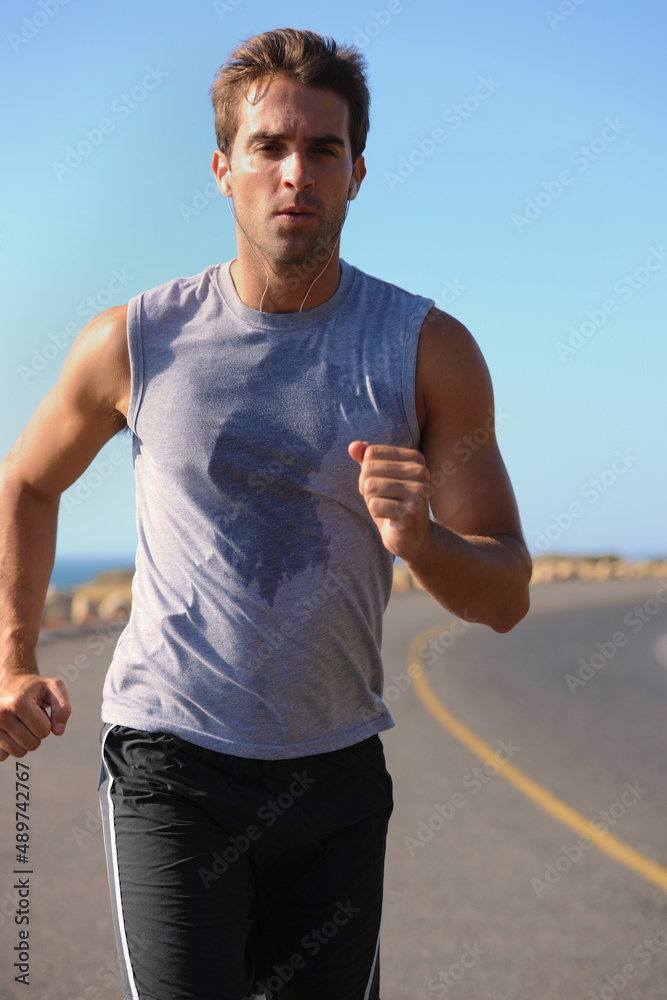 慢跑让我的心、身体和思想保持良好状态。英俊的年轻人在路上慢跑。