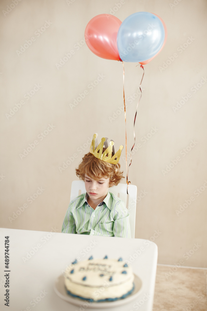 也许每个人都忘记了我的生日。一个可爱的小男孩坐在餐桌旁看起来不开心的照片