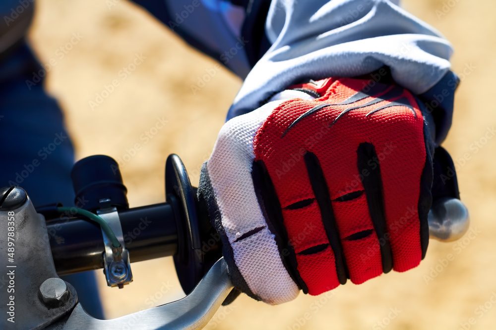 在摩托车越野赛中，保护双手至关重要。一只戴着手套的土自行车手的特写。